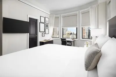 a white bedroom with a large bed and windows at The Gregorian New York City in New York