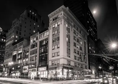 a tall white building on a city street at night at U Hotel Fifth Avenue, Empire State Building in New York