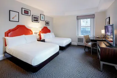 a hotel room with two beds and a desk and a television at The Lexington Hotel, Autograph Collection in New York