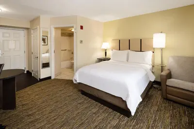 a hotel room with a bed and a chair at Candlewood Suites Windsor Locks by IHG in Windsor Locks
