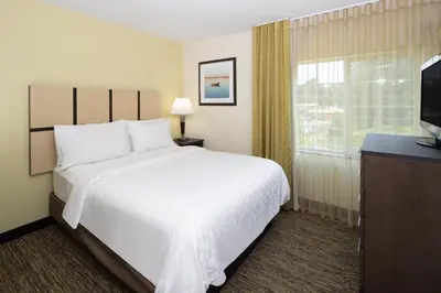 a hotel room with a large white bed and a window at Candlewood Suites Windsor Locks by IHG in Windsor Locks
