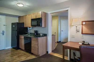 a small kitchen with a black refrigerator and a table at Candlewood Suites Windsor Locks by IHG in Windsor Locks