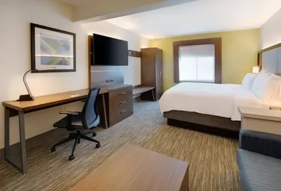 a hotel room with a bed and a desk with a computer at Holiday Inn Express & Suites Bradley Airport by IHG in Windsor Locks