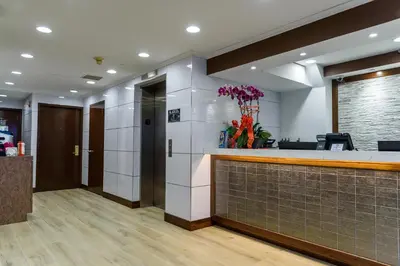 an office lobby with a reception counter and flowers at Flushing Central Hotel 88 in Queens