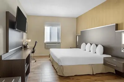 a hotel room with a bed and a flat screen tv at Best Western Jamaica Inn in Queens