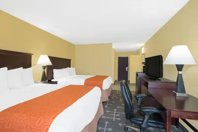 a hotel room with two beds and a desk and a television at Howard Johnson by Wyndham Saugerties in Saugerties