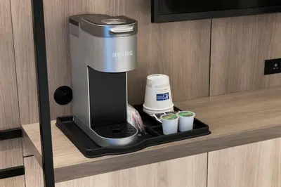 a coffee maker on a shelf with cups on it at Holiday Inn Express NYC Chelsea - NoMad Area by IHG in New York