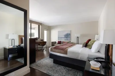 a bedroom with a bed and a desk and a mirror at The Andrew Hotel in Great Neck