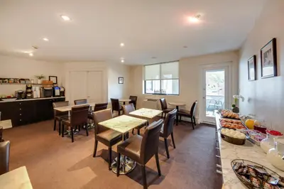 a dining room with tables and chairs and a kitchen at The Andrew Hotel in Great Neck