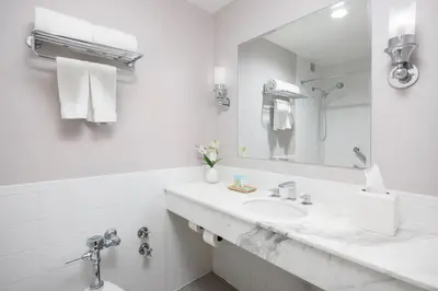 a white bathroom with a sink and a mirror at The Andrew Hotel in Great Neck