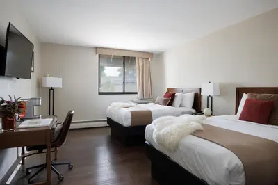 a hotel room with two beds and a desk at The Andrew Hotel in Great Neck