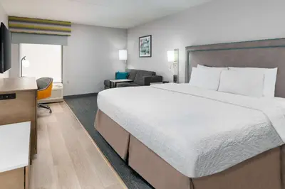 a hotel room with a large bed and a chair at Hampton Inn Hartford Airport in Windsor Locks