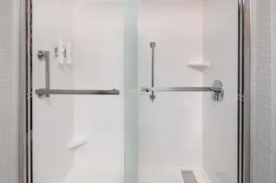 a bathroom with a shower and a glass door at Hampton Inn Hartford Airport in Windsor Locks