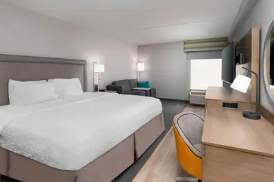 a hotel room with a large bed and a desk at Hampton Inn Hartford Airport in Windsor Locks
