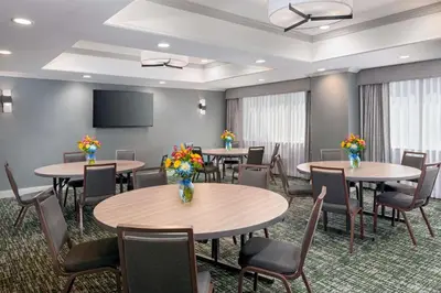 a conference room with tables and chairs and a screen at Hampton Inn Hartford Airport in Windsor Locks