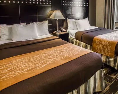 a hotel room with two beds and a lamp at Rodeway Inn Bronx Zoo in Bronx