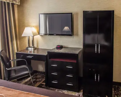 a hotel room with a desk with a television on the wall at Rodeway Inn Bronx Zoo in Bronx