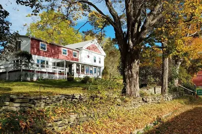 a large red and white house with a tree at The Open Door in Jefferson NY in Jefferson