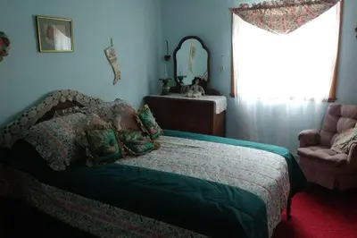 a bedroom with a bed and a chair and a window at The Open Door in Jefferson NY in Jefferson
