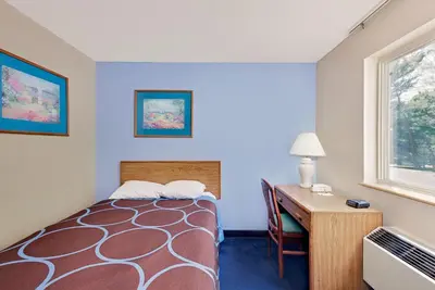 a room with a bed and a desk and a window at Super 8 by Wyndham Newburgh/West Point Stewart Intl Airport in Newburgh