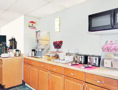 a kitchen with wooden cabinets and a tv on the wall at Super 8 by Wyndham Newburgh/West Point Stewart Intl Airport in Newburgh