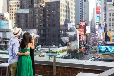 a man and woman taking a picture of a city at M Social Hotel New York Times Square in New York