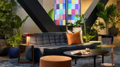 a living room with a couch and tables and plants at M Social Hotel New York Times Square in New York