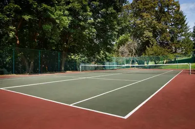 a tennis court with trees and a fence at Tarrytown House Estate in Tarrytown