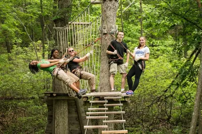 a group of people on a suspension bridge in the forest at Skytop Lodge in Skytop