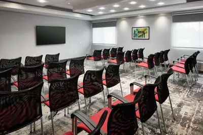 a room with a bunch of chairs and a flat screen tv at Hampton Inn Newark Airport in Newark