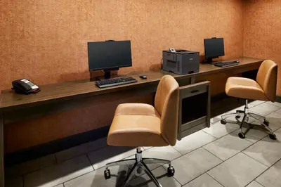 a desk with two computer monitors and two chairs at Hampton Inn Newark Airport in Newark