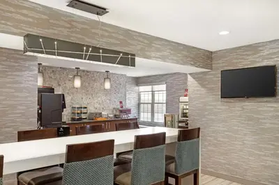 a kitchen with a bar with chairs and a flat screen tv at Best Western Plus Fairfield Hotel in Fairfield