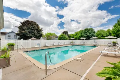 a swimming pool with chairs and a fence at Best Western Hartford Hotel and Suites in Hartford