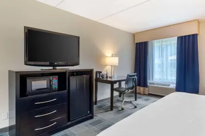 a hotel room with a bed and a desk with a television at Best Western Hartford Hotel and Suites in Hartford