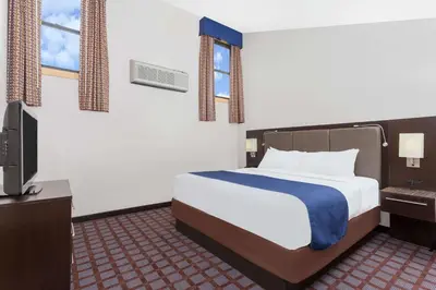 a hotel room with a bed and a tv at Days Inn by Wyndham Woodbury Long Island in Woodbury