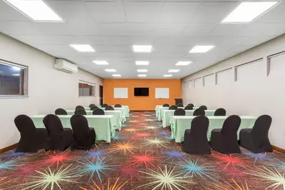 a conference room with green tables and chairs on a carpet at Days Inn by Wyndham Woodbury Long Island in Woodbury