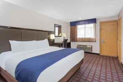 a hotel room with a large bed and a desk at Days Inn by Wyndham Woodbury Long Island in Woodbury
