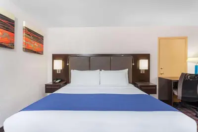 a bedroom with a large bed with a blue blanket at Days Inn by Wyndham Woodbury Long Island in Woodbury