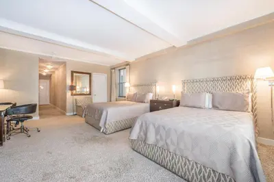 a hotel room with two beds and a desk at Lombardy Hotel in New York