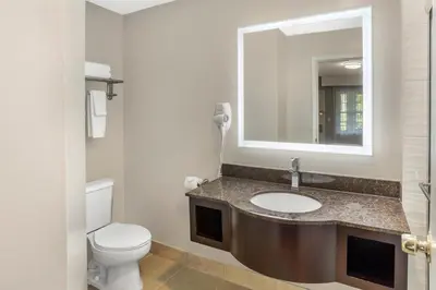 a bathroom with a sink and a toilet and a mirror at Best Western Fort Lee in Fort Lee