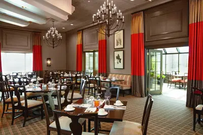 a dining room with tables and chairs and chandeliers at Ethan Allen Hotel in Danbury