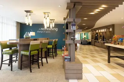 a restaurant with a bar with green chairs at EVEN Hotel Norwalk by IHG in Norwalk