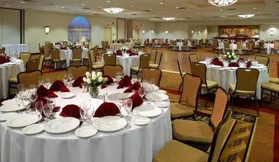 a banquet hall with white tables and chairs with red napkins at Clinton Inn Hotel Tenafly in Tenafly
