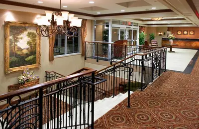 a lobby with a staircase with a chandelier at Clinton Inn Hotel Tenafly in Tenafly