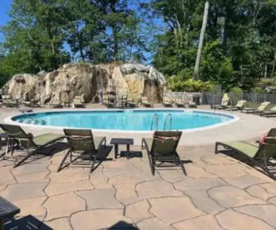 a pool with chairs and a table and a rock formation at The Abbey Inn & Spa in Peekskill