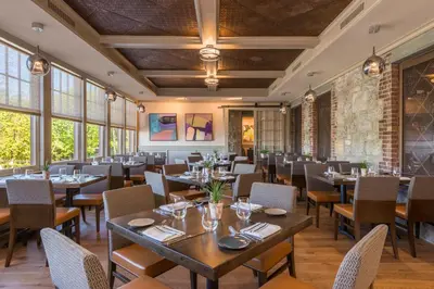 a dining room with tables and chairs and windows at The Abbey Inn & Spa in Peekskill
