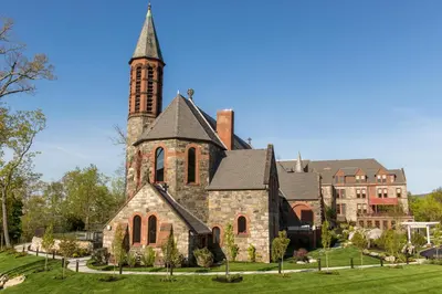 an old church with a tower on a green lawn at The Abbey Inn & Spa in Peekskill