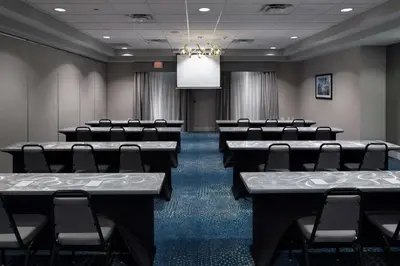 a conference room with tables and chairs and a chandelier at Homewood Suites by Hilton Newburgh-Stewart Airport in New Windsor