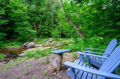a blue bench and a picnic table next to a creek at Mountain Treasure Bed and Breakfast in Maplecrest