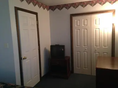a bedroom with a door and a small tv at Fred's Inn Restaurant & Lodging in Norwich